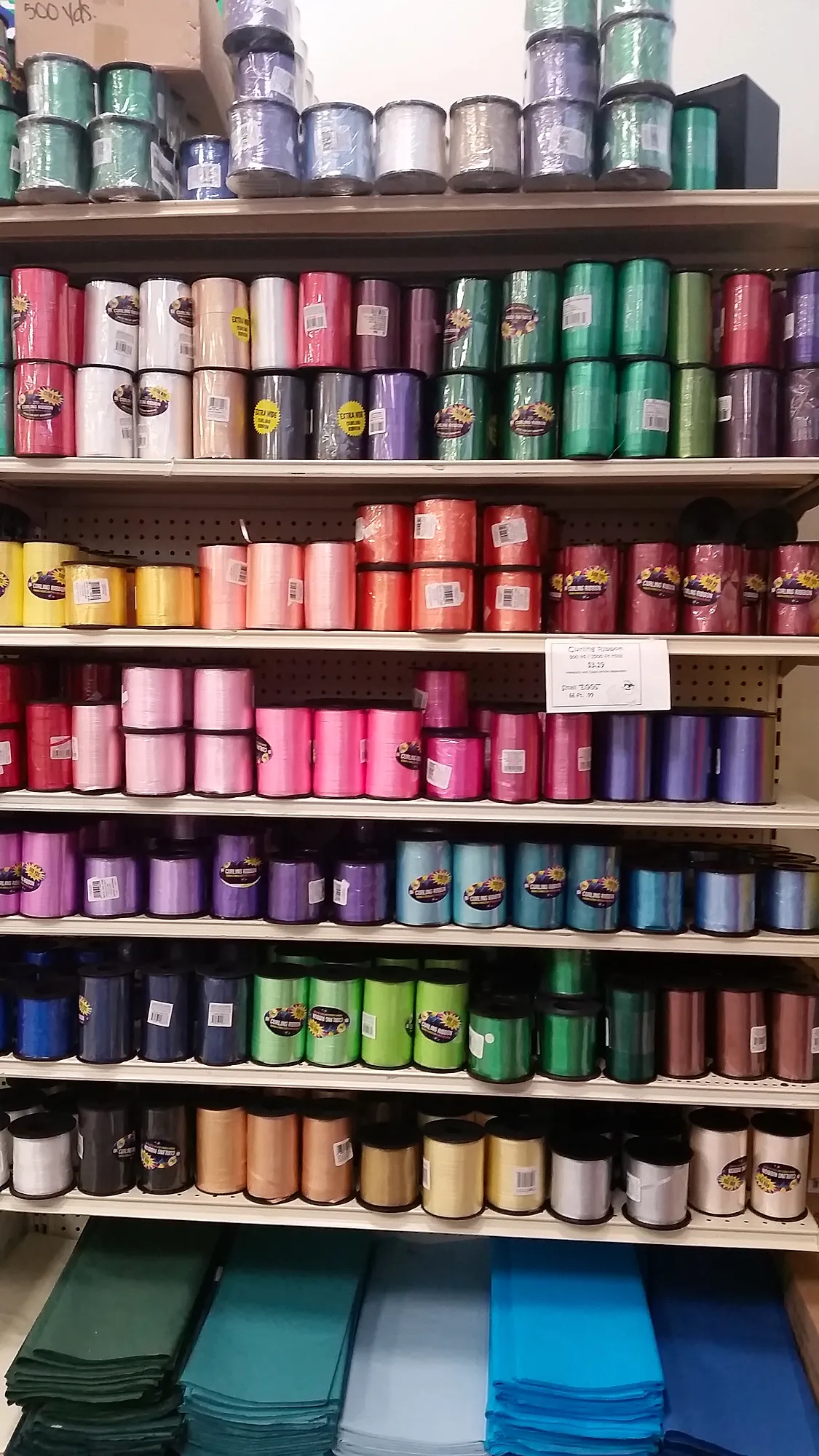 Floor-to-ceiling wall of curling ribbon spools in many colors